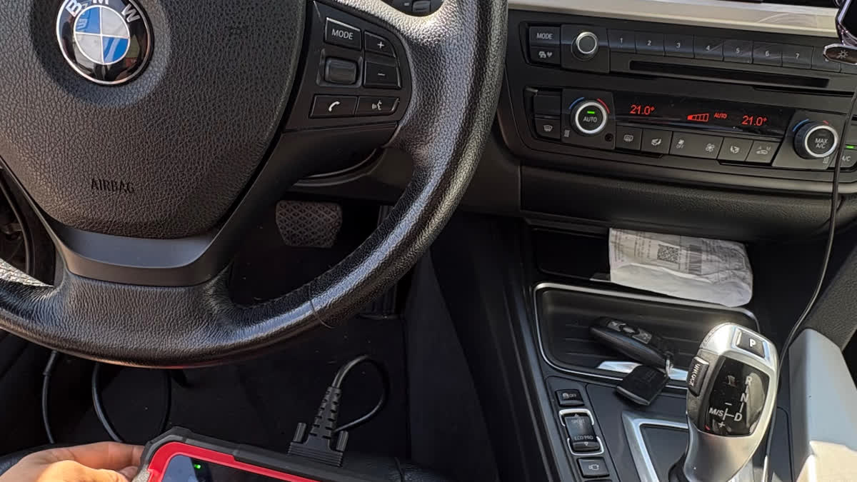 Meistars ar OBD-II diagnostikas iekārtu pie auto paneļa — mobilā datordiagnostika izbraukumā